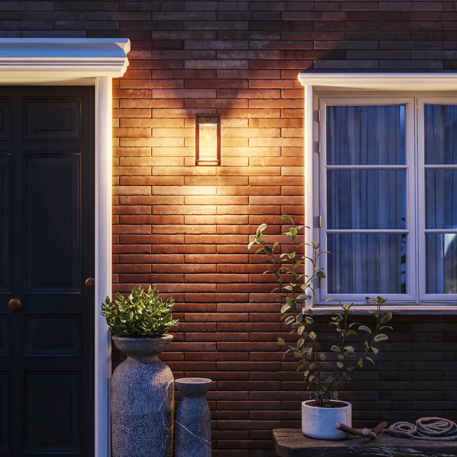 Foto einer leuchtenden, schwarzen Philips Geri Solar Wandleuchte an einer Backsteinwand.