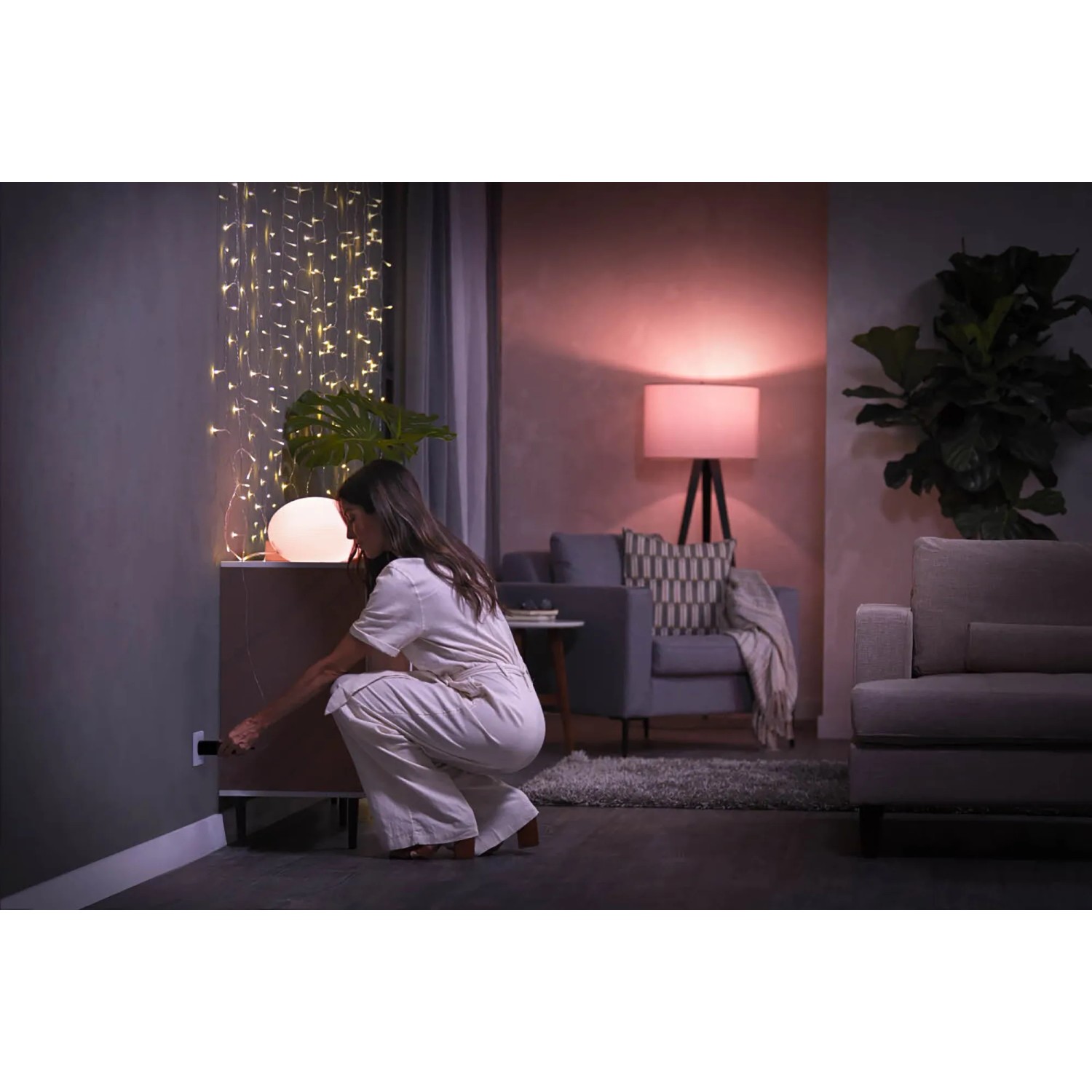 Frau steckt Philips Hue SmartPlug in die Steckdose. 4er Pack Hue Zwischenstecker für smarte Lampen und Geräte.