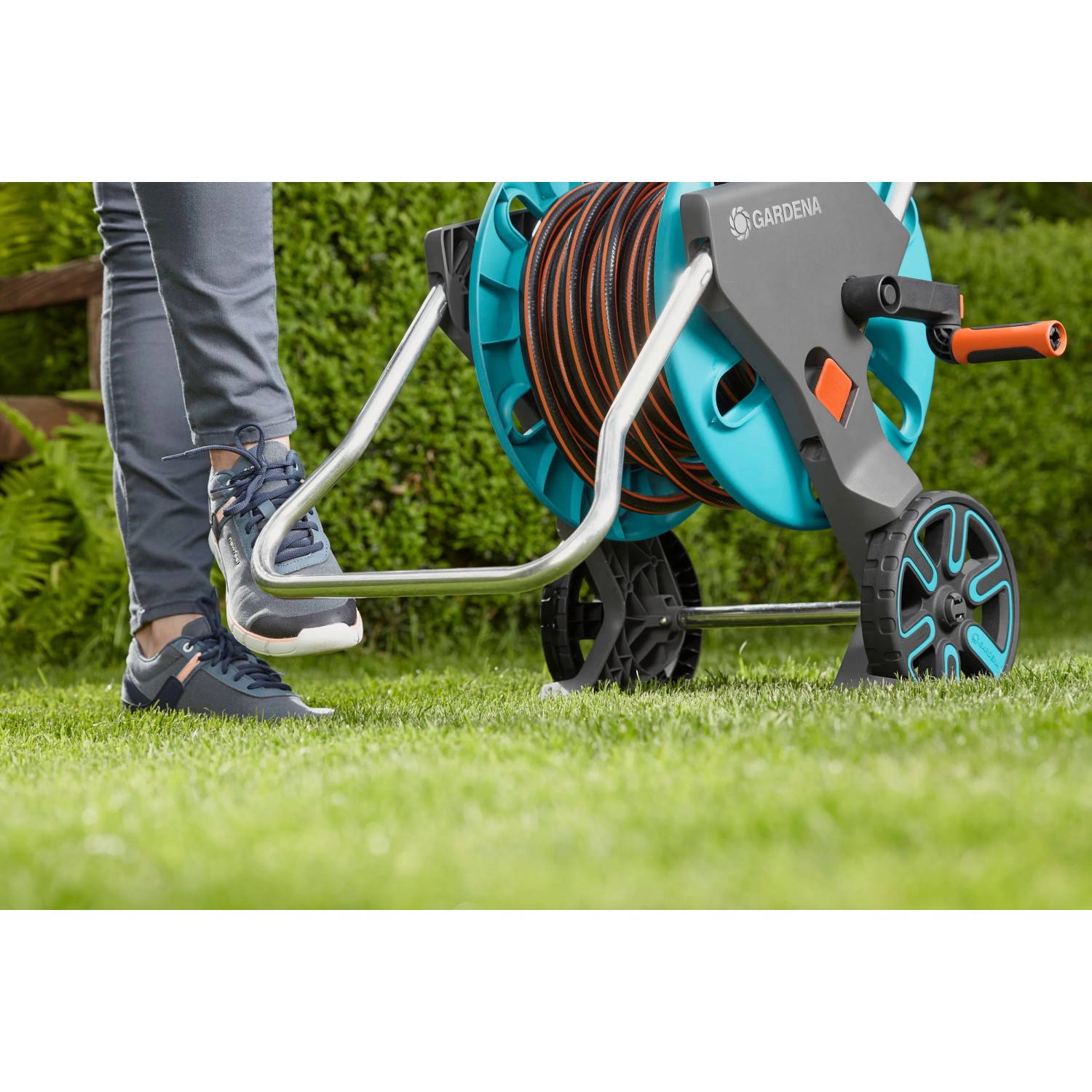 Gardena CleverRoll M Easy Schlauchwagen mit Schlauch auf Rasen, Fuß auf Standfuß.