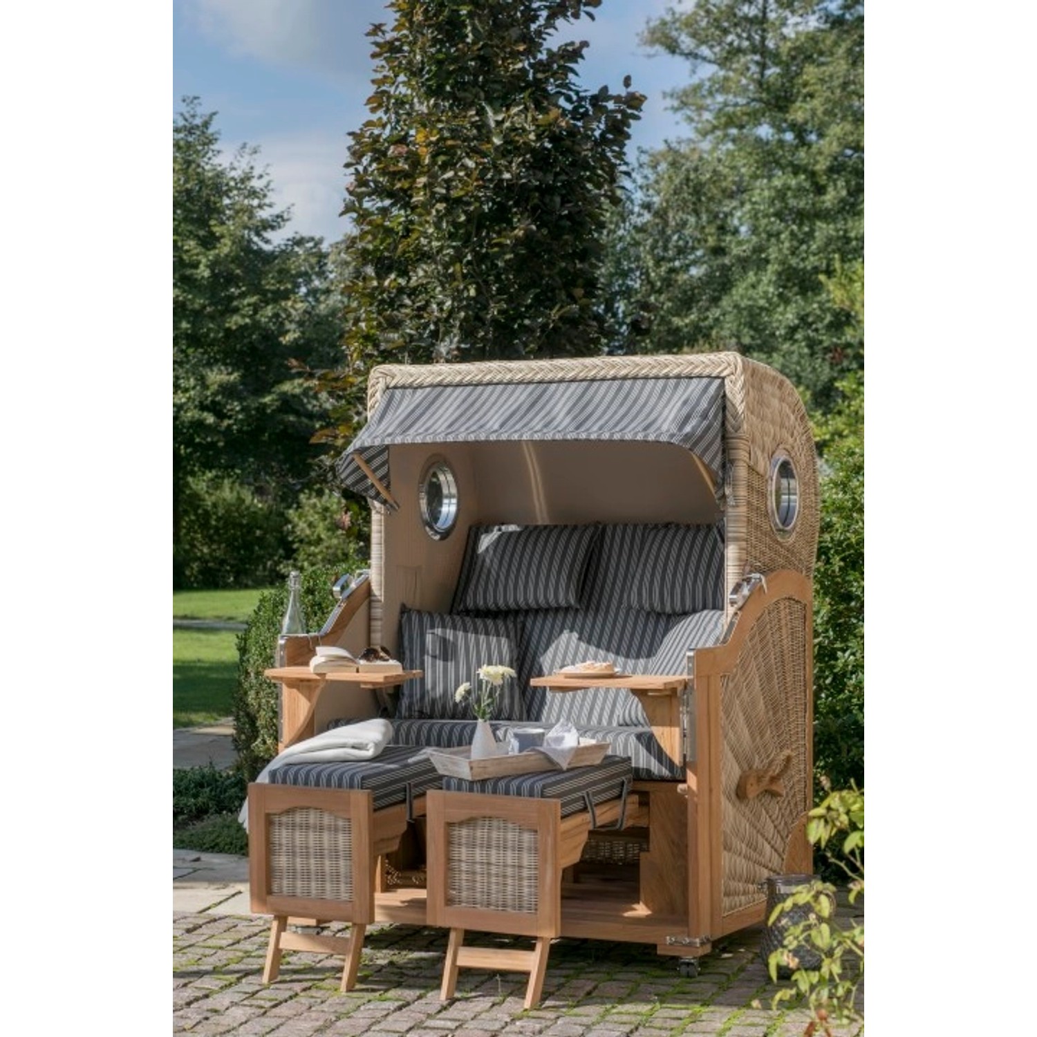 GarWoh Strandkorb Rantum Teak mit PE-Geflecht und blau-weiß gestreiften Polstern.