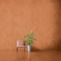 Raum mit Alpina Mineral Beton Effektfarbe in Terracotta, Stuhl und Pflanze.