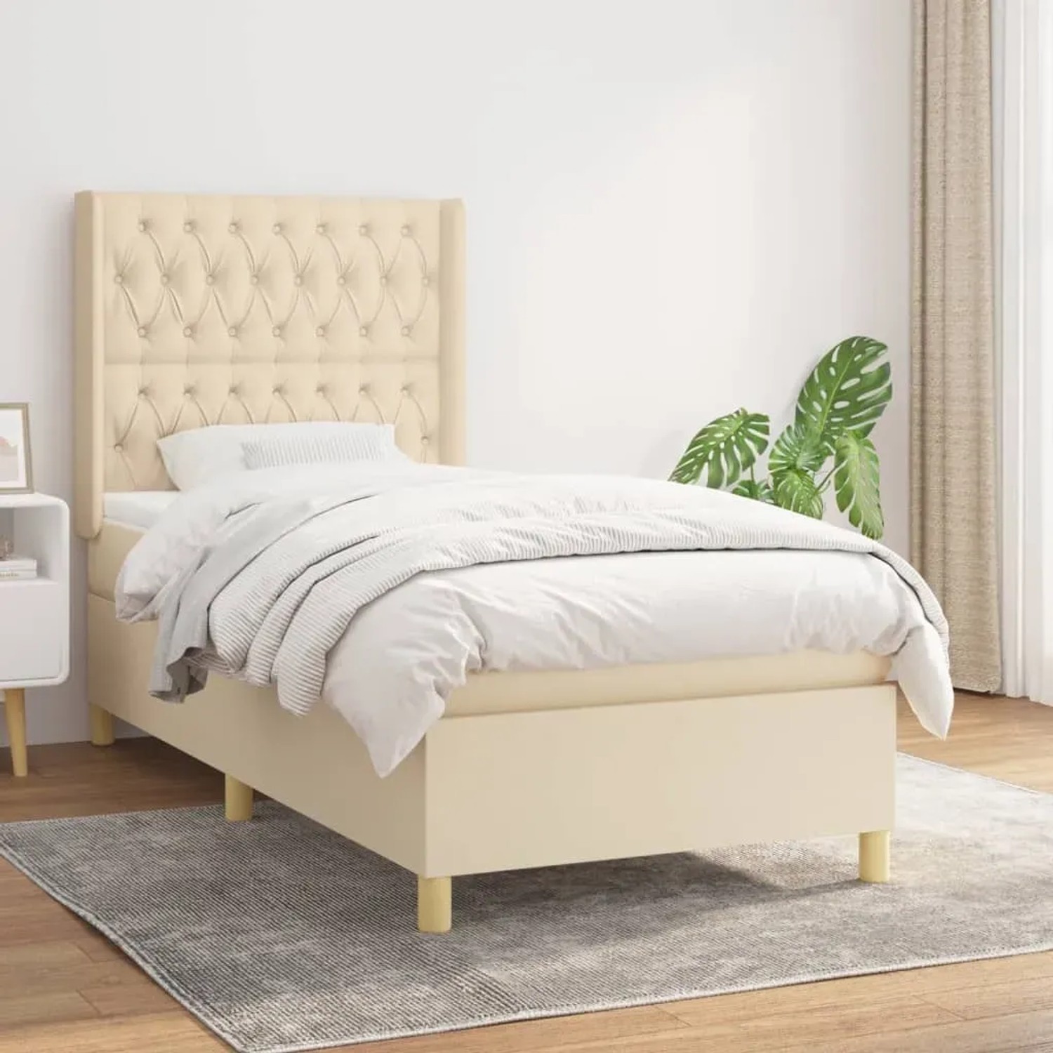 Cremefarbenes Boxspringbett (90x190 cm) mit Matratze und gestepptem Kopfteil.