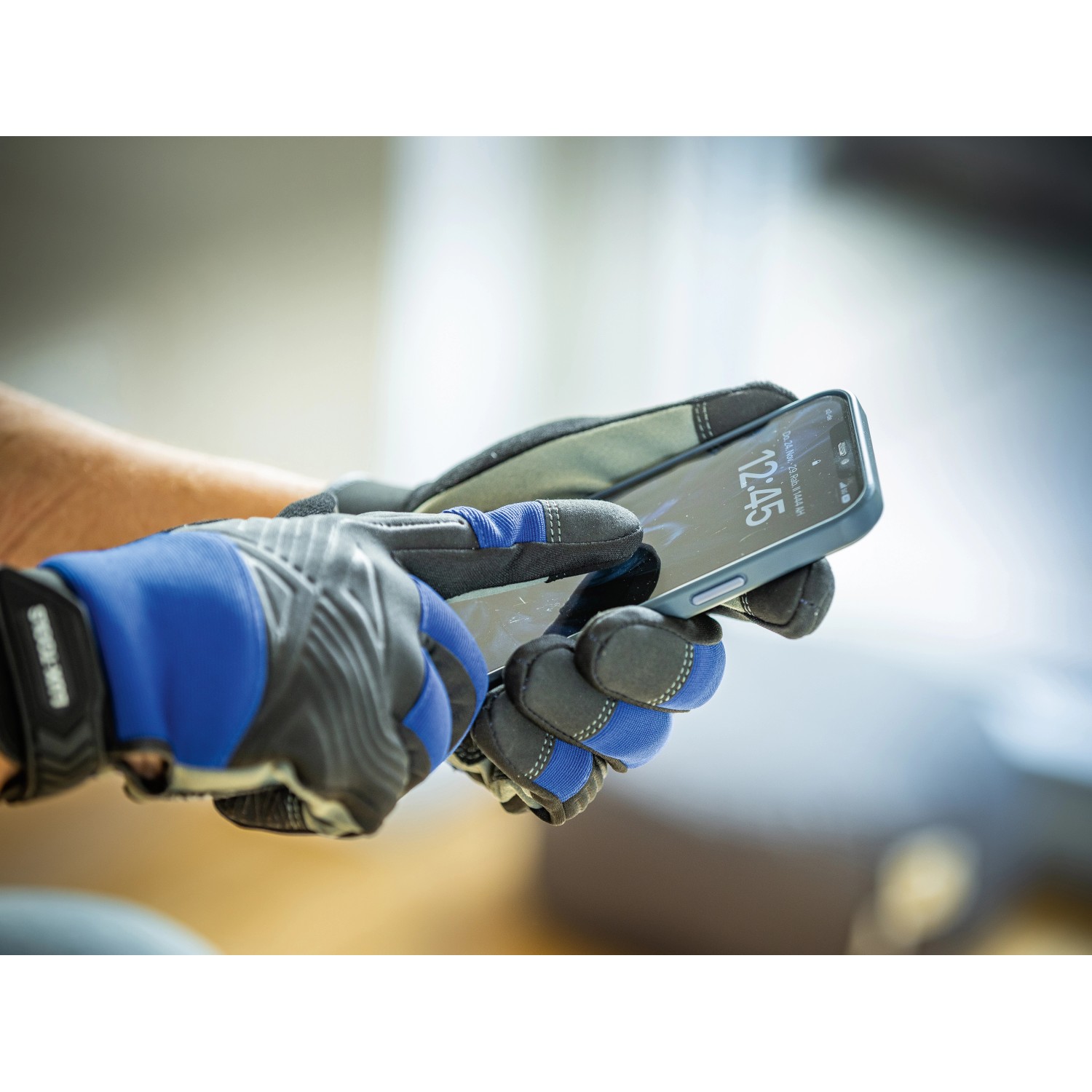 Hände mit LUX Arbeitshandschuhen Tough Gr. 10 bedienen ein Smartphone.
