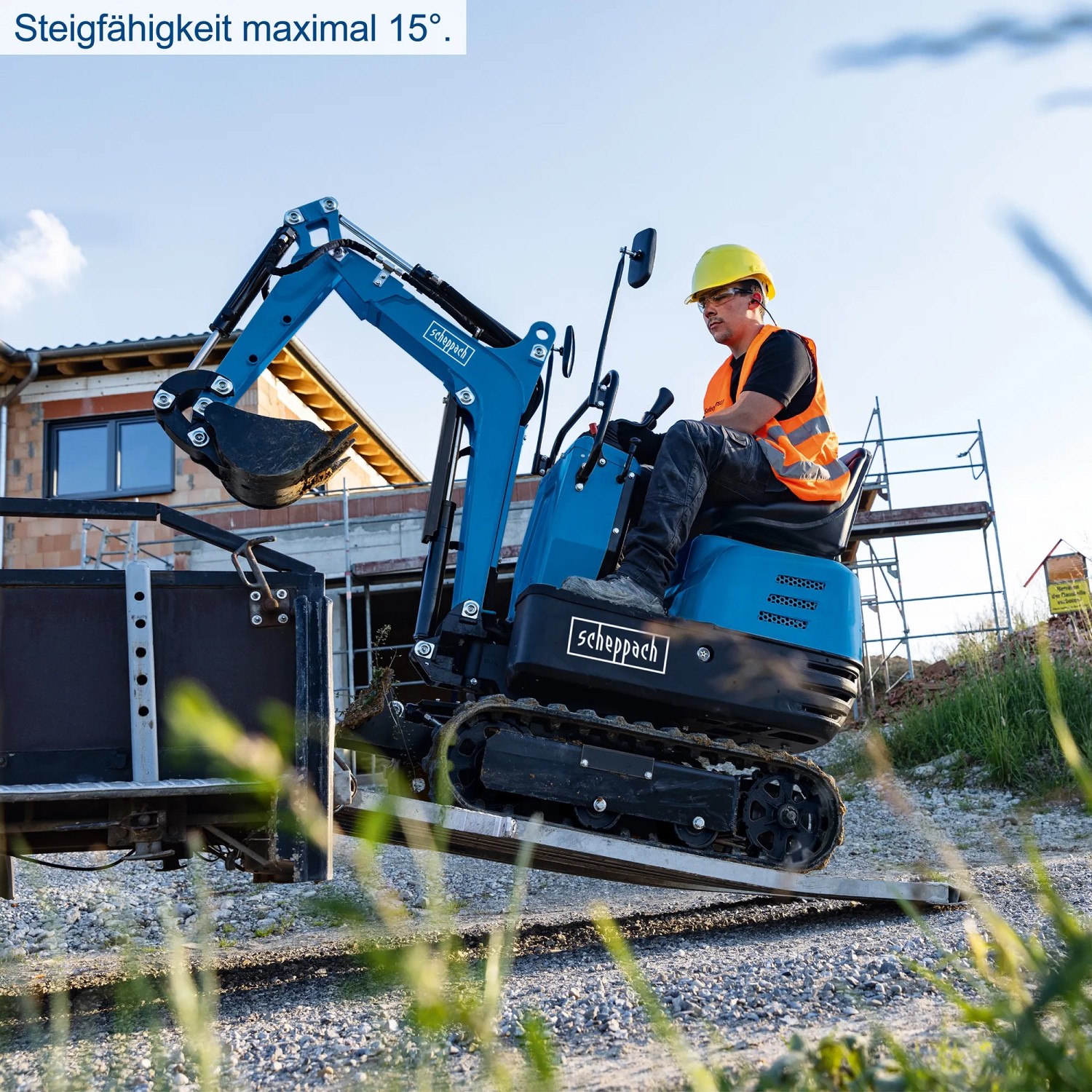 Scheppach Mini-Bagger EXC815: Blauer Bagger mit Fahrer auf Rampe, Baumaschine für Grabarbeiten.