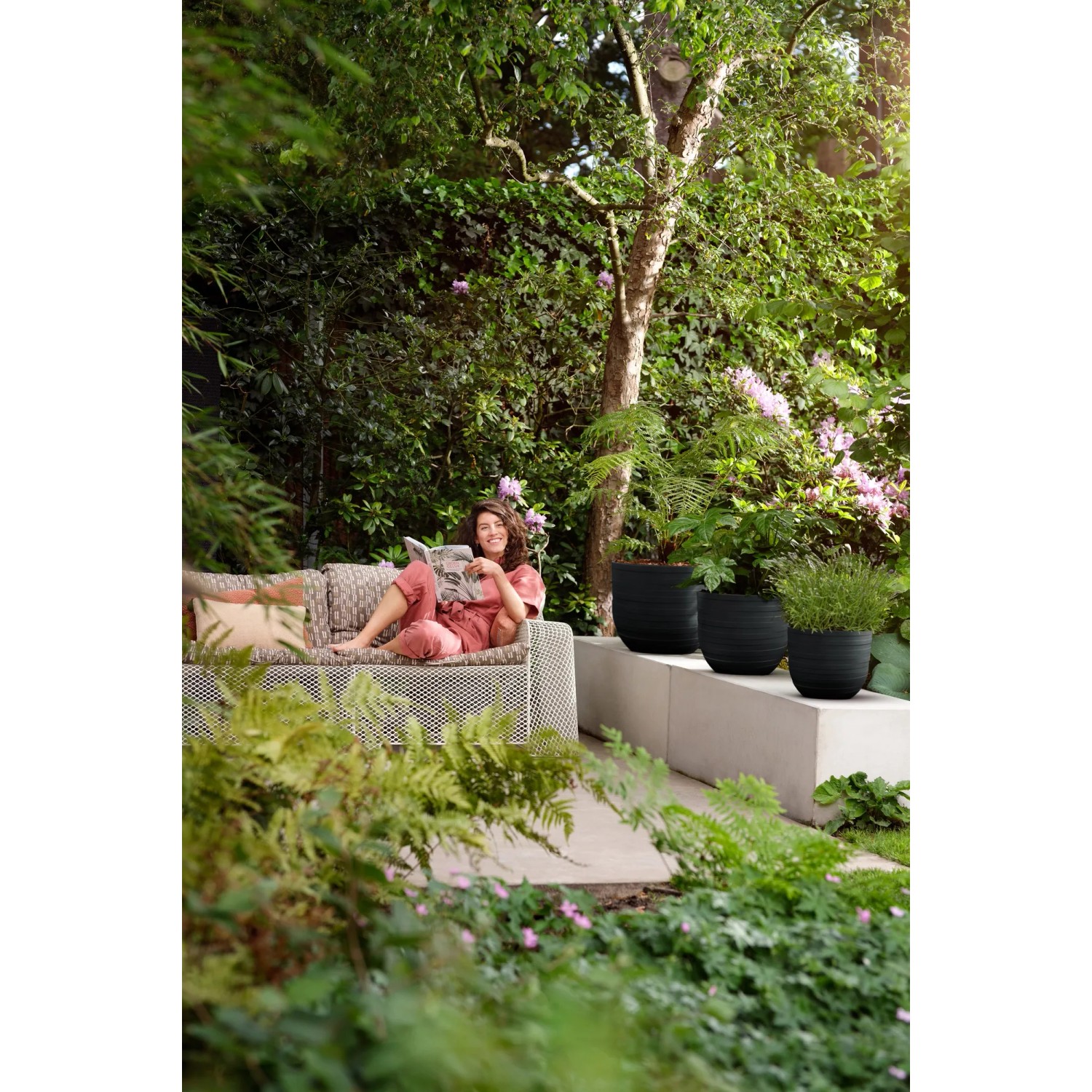 Elho Blumentopf Fuente Rings in Onyx Schwarz im Garten, kombiniert mit passenden Pflanzen.