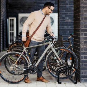 Anthrazitfarbener Fahrradständer für 3 Fahrräder mit Mann und Fahrrad.