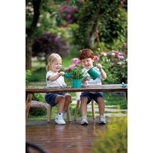 Zwei Kinder spielen mit dem Hape Gartenwerkzeug-Set (Gießkanne, Schaufel) im Garten.