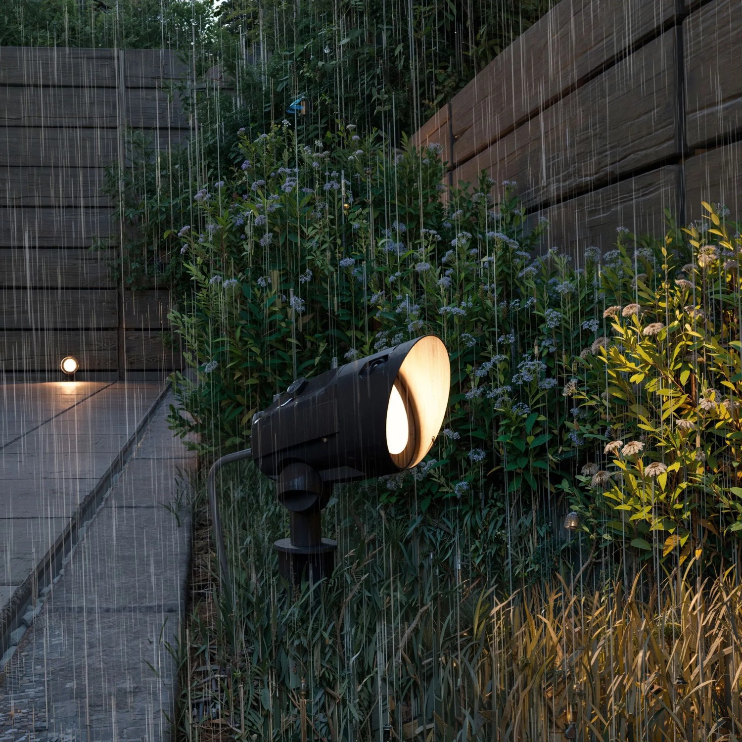 Schwarze Philips Cylr LED-Gartenstrahler Erdspießleuchte im Regen, warmweißes Licht.