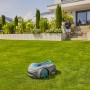 Gardena Sileno Smart Free Mähroboter auf Rasen vor Haus mit Mann. Kabelloser Rasenmäher für bis zu 600 m².