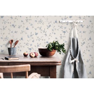 Vliestapete mit blau-beigem Blümchenmuster im Landhausstil an einer Wand in einer Küche mit Holztisch und Deko.