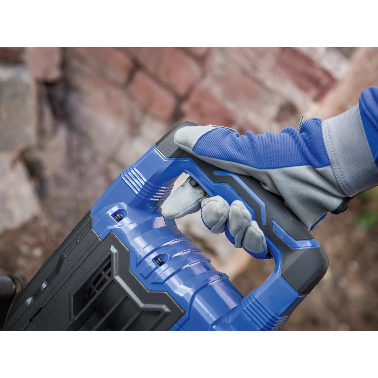 Detailaufnahme: Hand mit Handschuh am Griff des blauen LUX Abbruchhammers. Baumaschine für Abbrucharbeiten.
