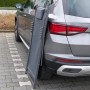 Zusammengeklappte, anthrazitfarbene FIFITARA Sonnenliege aus Metall, angelehnt an ein Auto.