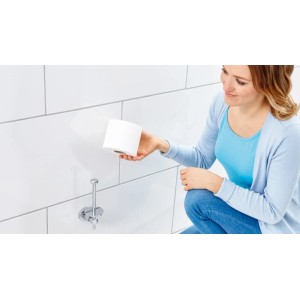 Frau hält Toilettenpapier neben Tesa Ersatz-Toilettenpapierhalter Loxx verchromt an weißer Wand.