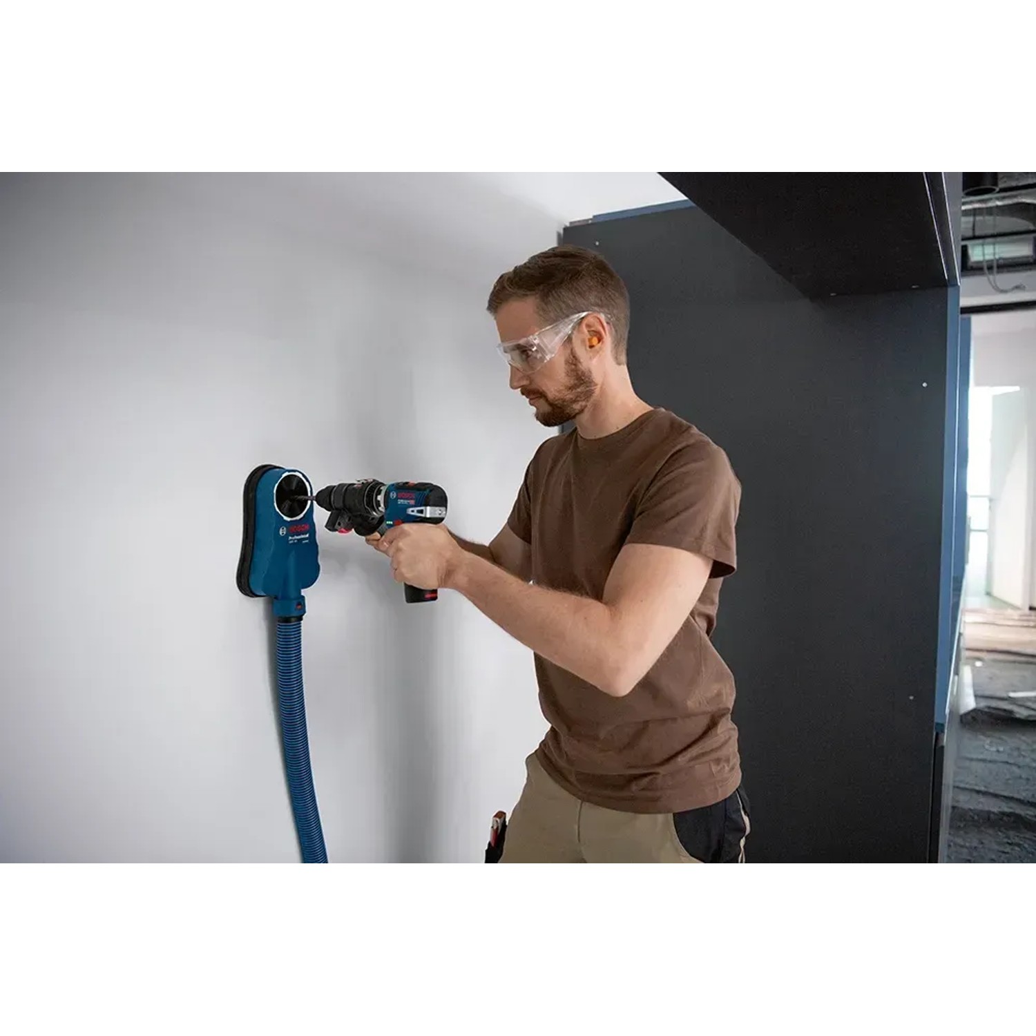 Mann bohrt mit Bosch Professional FlexiClick Bohrhammeraufsatz GFA 12-H in Wand.