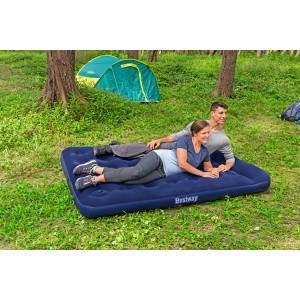 Blaues Doppelluftbett mit Fußpumpe von Bestway, zwei Personen liegen entspannt darauf. Camping im Grünen.