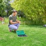 Mann bedient Gardena Bewässerungsventil 9 V Bluetooth mit dem Smartphone im Garten.
