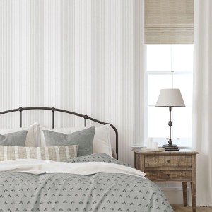 Graue Vliestapete mit feinen Streifen im Landhausstil, dekoriert ein Schlafzimmer mit Bett und Nachttisch. Ideal für Wandgestaltung.