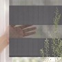 Graues SALCAR Doppelrollo Klemmfix am Fenster. Transparente und blickdichte Streifen, Hand zeigt Sichtschutzfunktion.