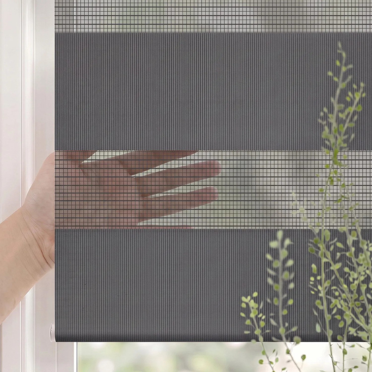 Graues SALCAR Doppelrollo Klemmfix am Fenster. Transparente und blickdichte Streifen, Hand zeigt Sichtschutzfunktion.