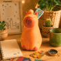 Gelbe Keramik Capybara Sparbüchse mit Geldschein und Münzen auf Holzschreibtisch. Kinderspardose, Geschenkartikel.