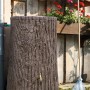 Dunkelbraune Arves Regentonne Evergreen 475 l in Baumstammoptik mit Auslaufhahn im Garten.