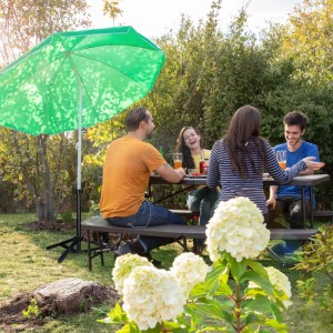 Schwarzer, klappbarer Relaxdays Sonnenschirmständer aus Stahl mit grünen Sonnenschirm im Garten mit Menschen.