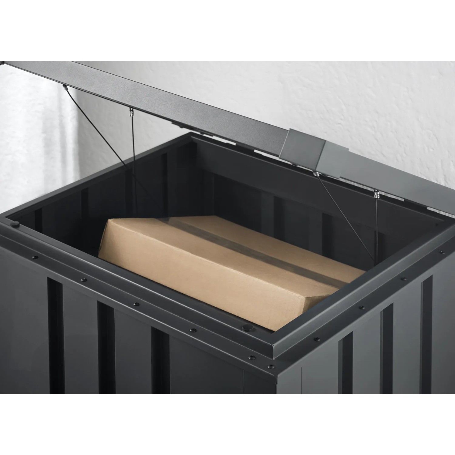 Offene, anthrazitfarbene Floraworld Paketbox aus Stahl mit Paket im Inneren.