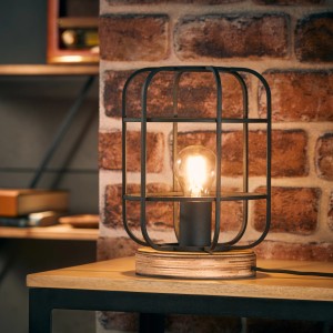 Brilliant Tischleuchte Gwen mit Holzfuß und schwarzem Metallkäfig. Schreibtischlampe im Industrial Design.