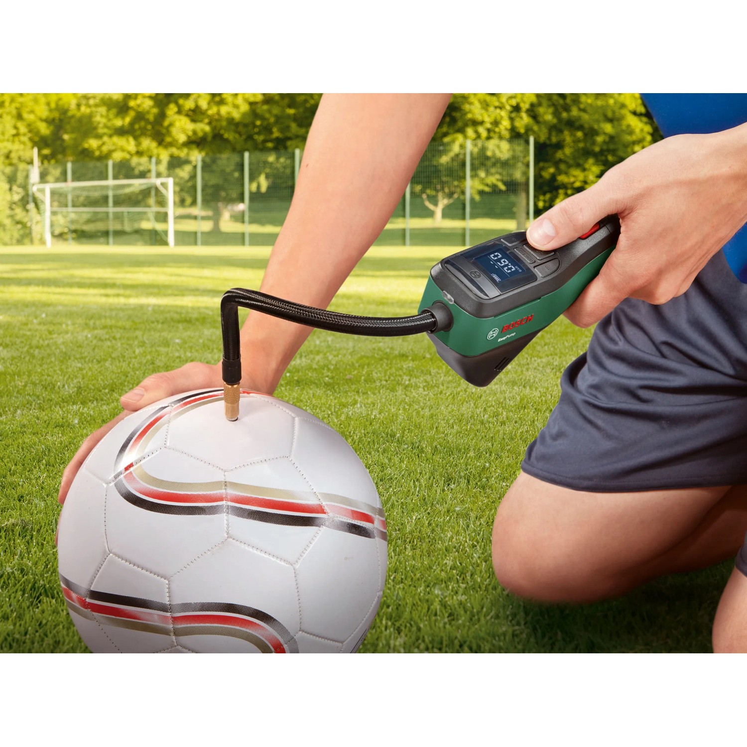 Bosch Easy Pump Akku-Druckluftpumpe beim Aufpumpen eines Balls auf einem Fußballfeld.