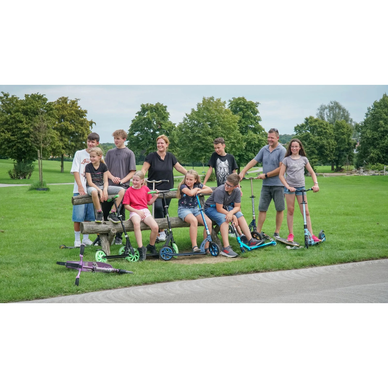 Gruppe mit Six Degrees Aluminium Scooter, hellblau, mit Klappmechanismus und Ständer im Park.
