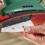 Hand befestigt Schleifpapier an roter Schleifplatte des grünen Bosch Akku-Multischleifers UniversalSander 18V-10.