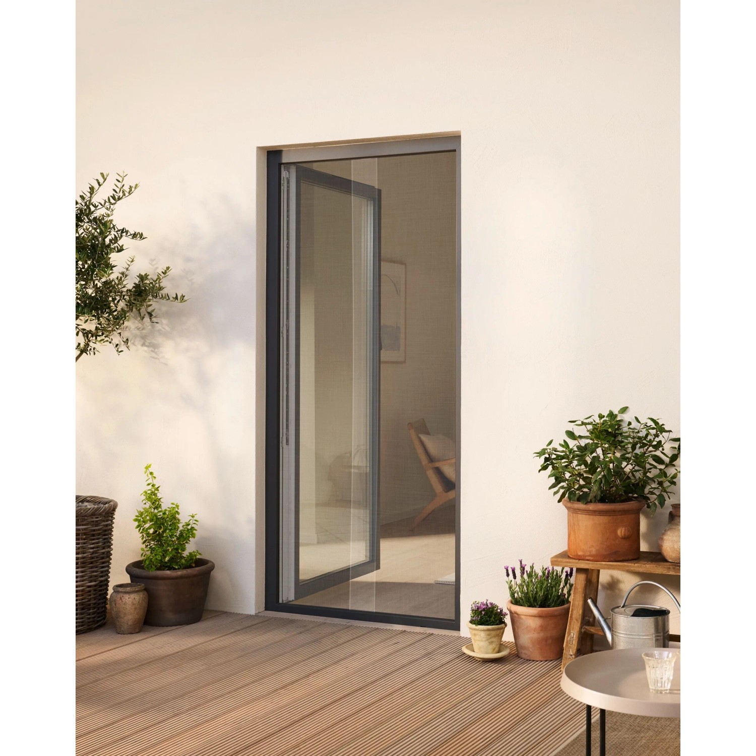 Weißes tesa® Insect Stop Fliegengitter Premium für eine Terrassentür mit dunklem Rahmen.