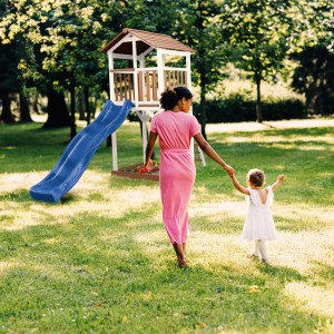 Axi Beach Tower Spielturm mit blauer Rutsche im Garten, Mutter mit Kind im Vordergrund.