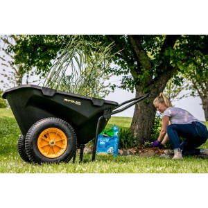 Schwarze Polar Schubkarre Cub Cart mit gelben Rädern und Frau bei Gartenarbeit.