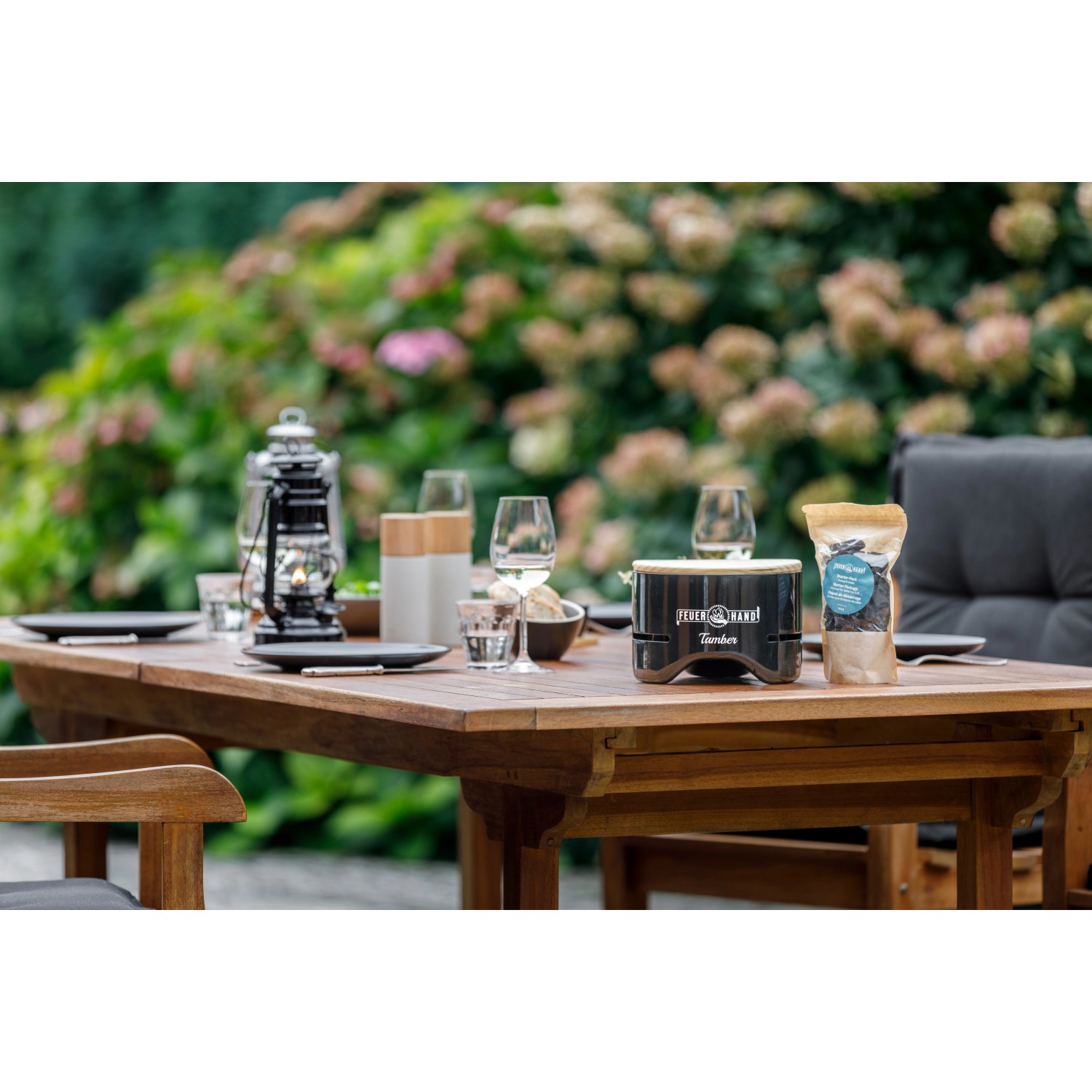 Feuerhand Tischgrill Tamber, tiefschwarz, mit Kohle auf gedecktem Gartentisch.