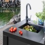 Buschbeck Outdoorküche Liverpool Schwarz mit Spüle und Armatur vor Gartenteich.