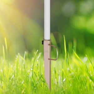 Verzinkter Stahl Rasendorn im Rasen, hält weißen Sonnenschirmmast. Mit Handgriff und Feststellschraube für stabilen Halt im Garten.