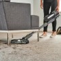 Ryobi Akku-Staubsauger RSVS18BL-0 in Aktion unter Sofa, mit Hund im Hintergrund.