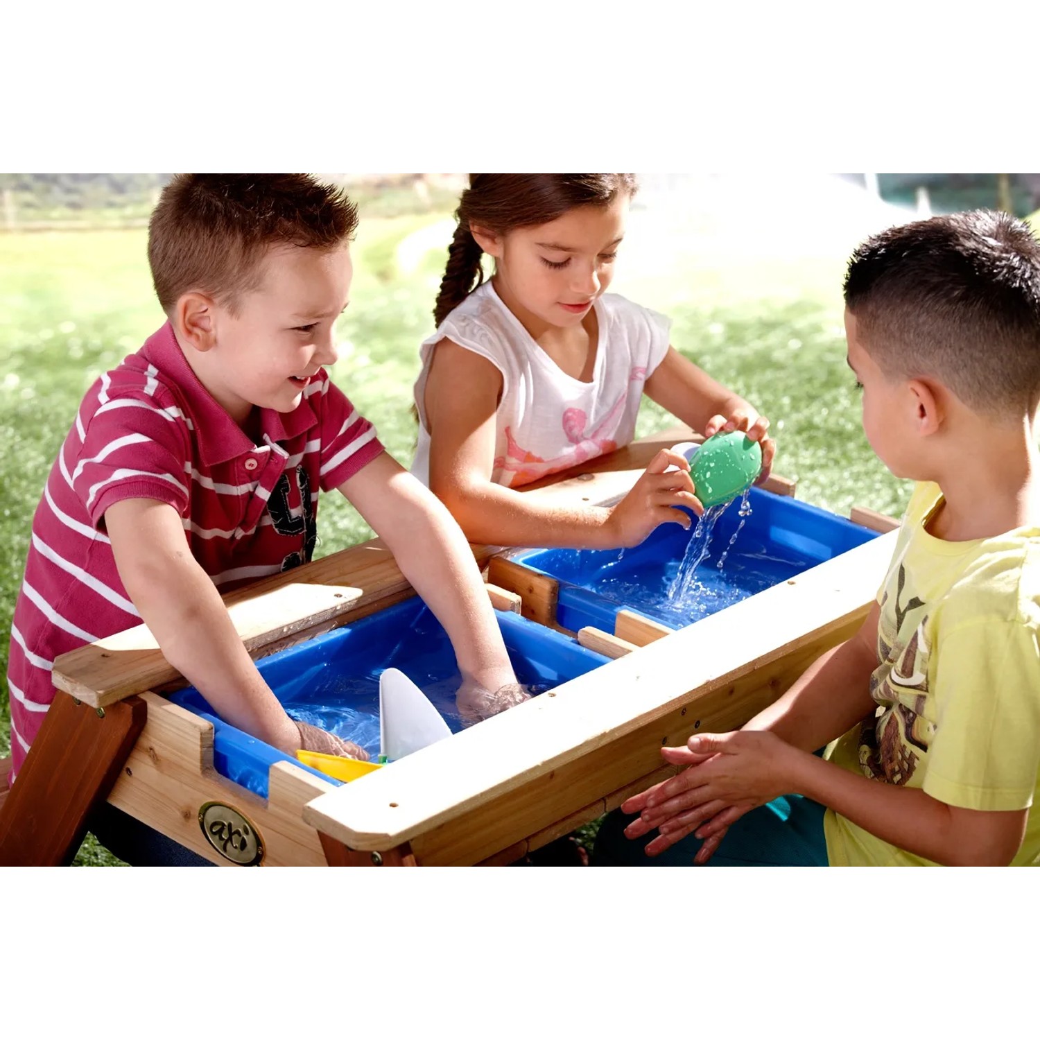 Kinder spielen am Sand- und Wasserspieltisch Nick Braun im Garten mit Wasser und Förmchen.