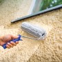 Hand streicht raue Wand mit LUX Dispersionswalze 25 cm. Farbwalze mit blauem Griff.