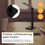 Schwarze ENOVALITE LED Schreibtischleuchte mit induktiver Ladestation auf einem Schreibtisch.