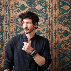 Mann vor Bricoflor Ethno Tapete in Petrol Braun mit marokkanischem Muster im Boho-Stil.