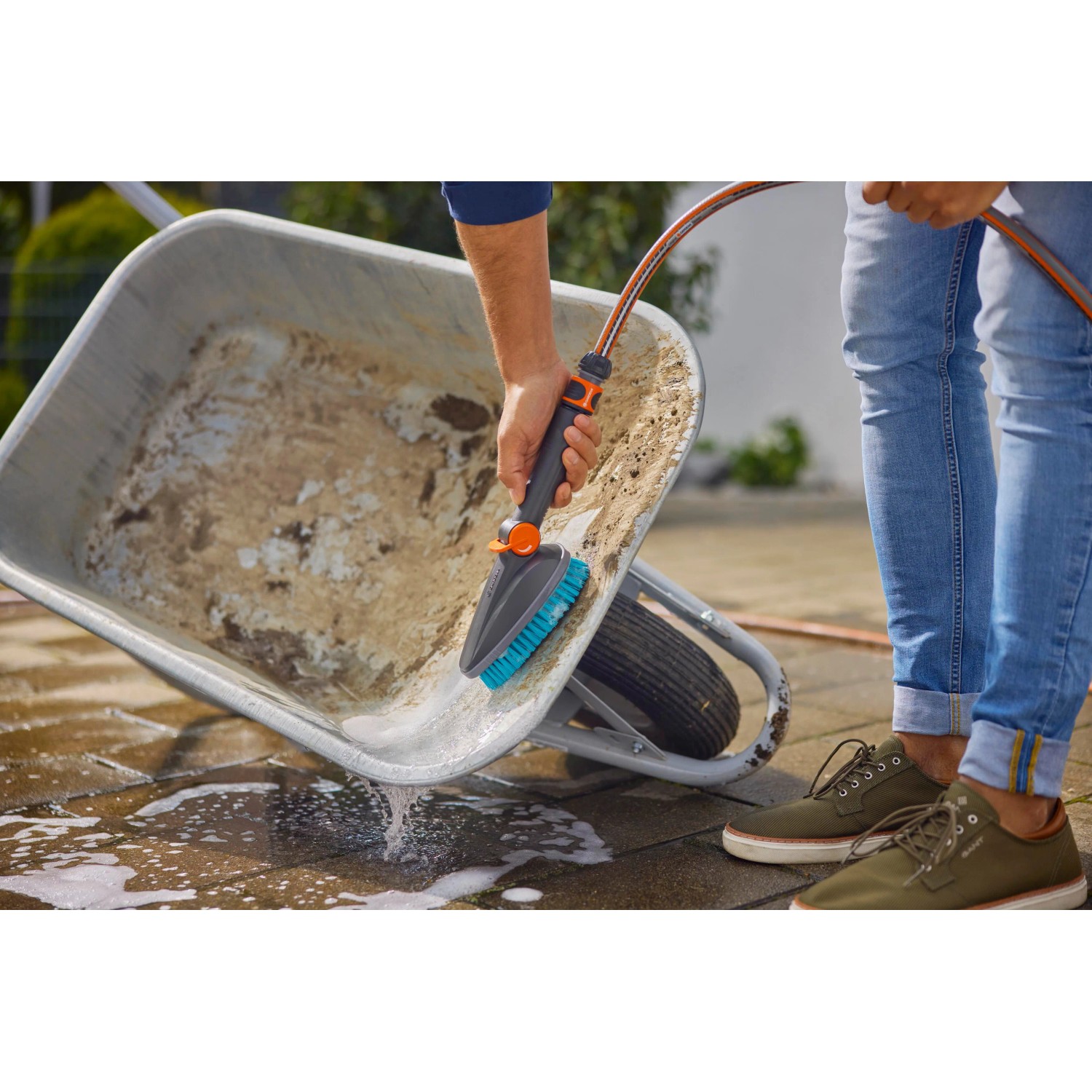 Gardena Cleansystem Handbürste M hard mit Schlauchanschluss beim Reinigen einer Schubkarre.