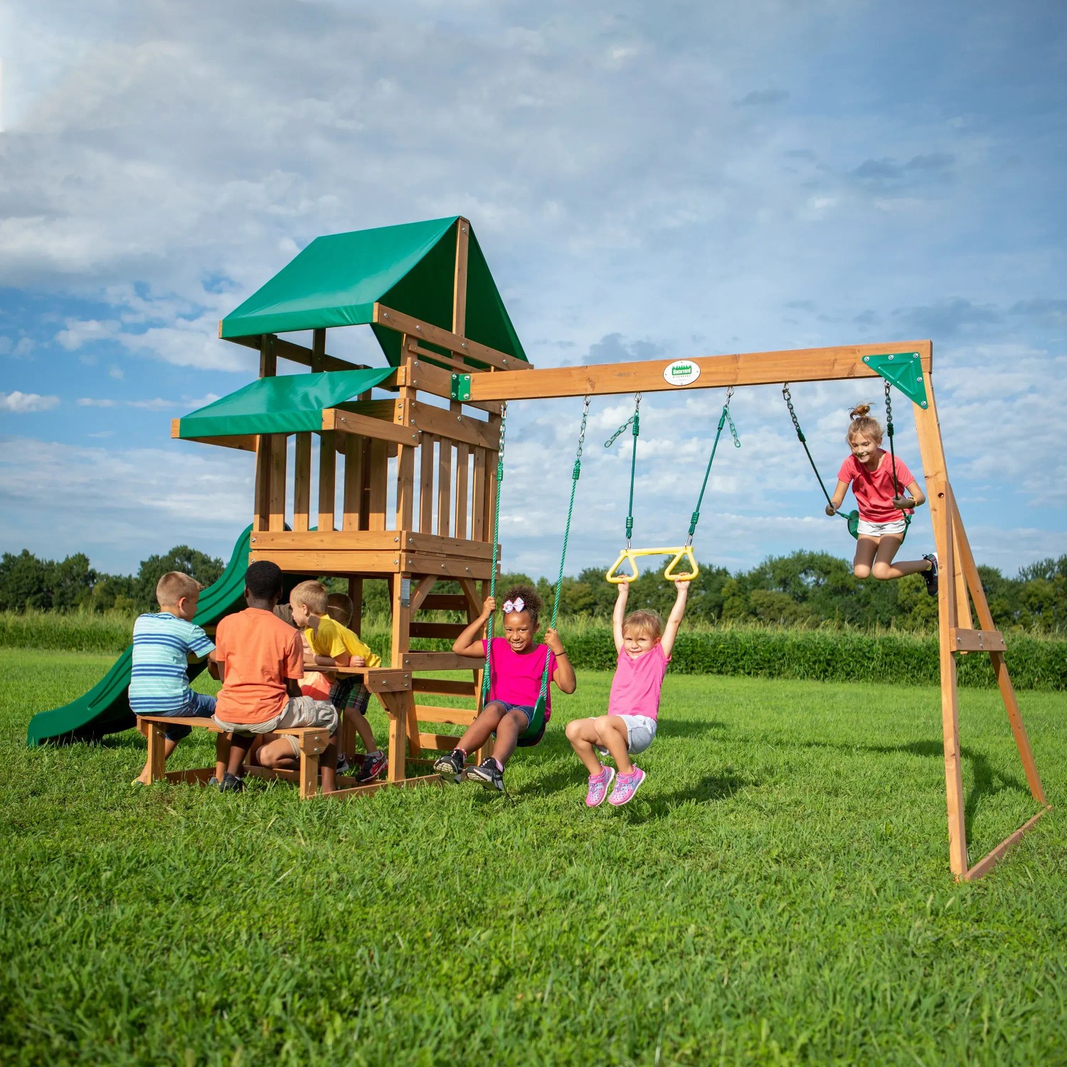 Backyard Discovery Belmont Spielturm mit Schaukeln, Rutsche und spielenden Kindern im Garten.