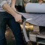 Mann schneidet Bodenbelag mit Fiskars Hardware-Schere (25 cm).
