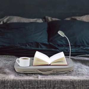 Graues Laptopkissen mit integriertem Licht und Getränkehalter auf einem Bett, ideal für Bürobedarf.