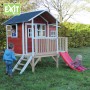 Rotes EXIT Loft 350 Holzspielhaus mit Rutsche, Anbau, Treppe und Geländer im Garten.
