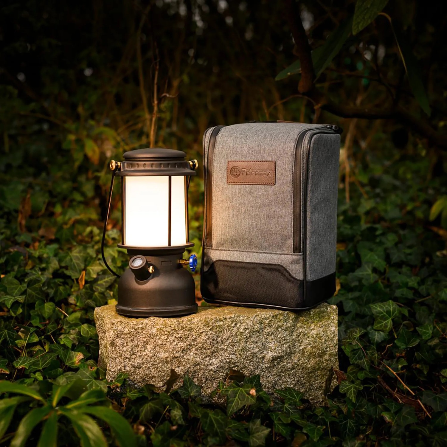 Petromax LED-Laterne PX-LM500 (schwarz) mit Tasche auf Stein im Grünen. Camping & Zubehör.