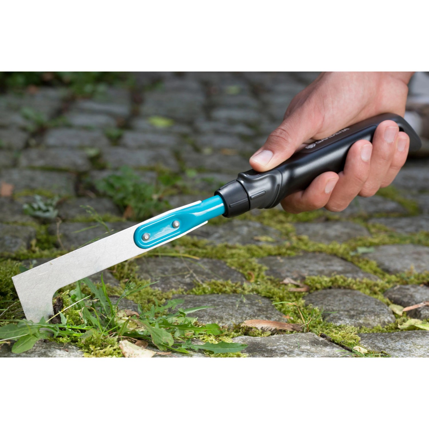 Gardena Fugenkratzer im Einsatz: Hand hält das Gartenhandgerät zum Entfernen von Unkraut.