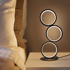 Moderne schwarze LED Tischlampe aus Aluminium mit drei leuchtenden Ringen auf Nachttisch. Dimmbare Innenleuchte.